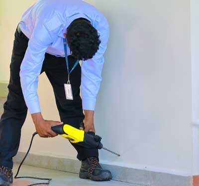 man drilling wall for termite treatment